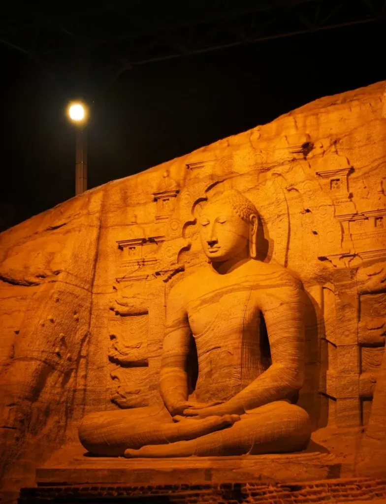 A stone Buddha statue at Polonnaruwa illuminated after dark
