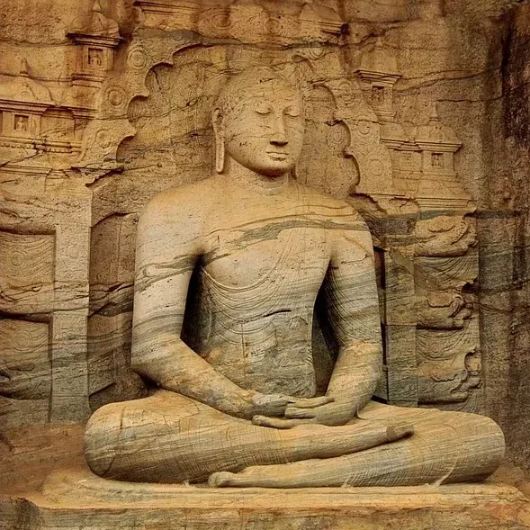 A weathered stone Buddha statue seated among the ancient ruins of Anuradhapura
